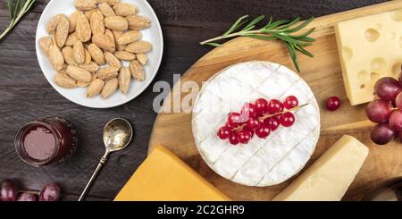 Cheese panorama. Camembert, Cheddar, Parmesan, and Edam, shot from the top on a dark rustic wooden background Stock Photo