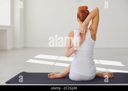 Slim woman practicing yoga in Cow Face pose Stock Photo
