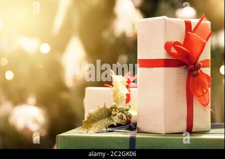Decorated gift boxes with lighted christmas tree on background Stock Photo