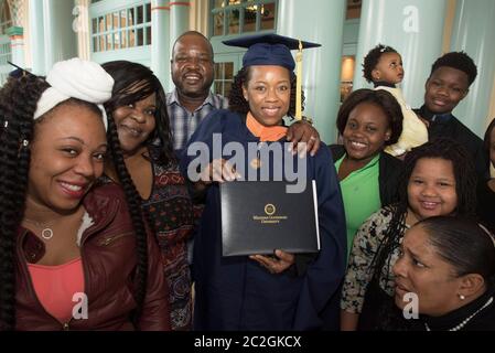 Orlando Florida USA, February 6, 2016: Black female graduate of Western Governor's University, a fully accredited online university that offers bachelors and masters degrees nationwide, poses in her cap and gown with her family after WGU's graduation ceremony.  ©Bob Daemmrich Stock Photo
