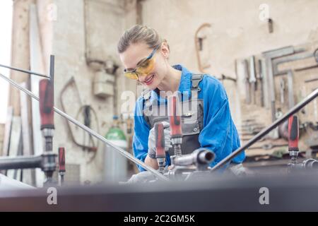 woman in Metal workshop with tools and workpiece working hard Stock Photo