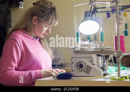 Girl engaged in needlework at a desk with a sewing machine Stock Photo