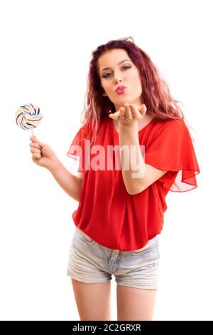 Beautiful fashionable young girl with a lollipop blowing a kiss to you, isolated on white background. Stock Photo
