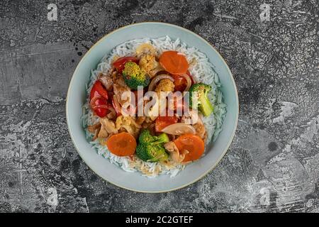 Grilled chicken, rice, spicy chickpeas, avocado, cabbage, pepper buddha bowl on dark background, top view. Delicious balanced food concept Stock Photo
