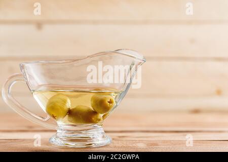 olive oil in a clear glass oil can with olives Stock Photo