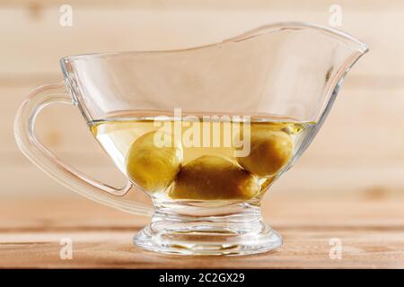 olive oil in a clear glass oil can with olives Stock Photo