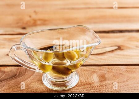 olive oil in a clear glass oil can with olives Stock Photo