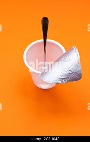 empty clean yogurt cup with spoon on an orange background Stock Photo