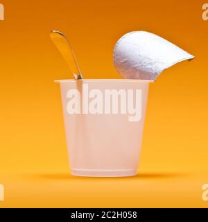 empty clean yogurt cup with spoon on an orange background Stock Photo