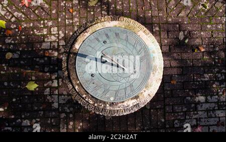 Top down photo of a stone and metal sundial on a mottled brick garden path Stock Photo