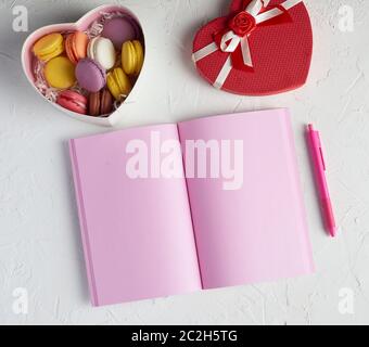 open notebook with blank pink pages, red pencil and a box of sweets, top view Stock Photo