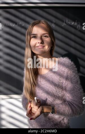 Pretty, young female student/teacher in front of a blackboard during math class Stock Photo