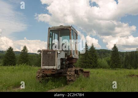 Old tractor on a field in the village in the summer Stock Photo