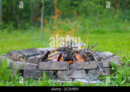 Refractory brick fireplace in focus and blurry bonfire in the background Stock Photo