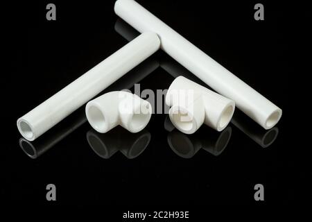 plastic pipe fittings on black isolated background, on black glass Stock Photo