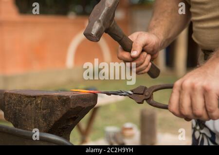 Blacksmith working on metal on an anvil in the forge Stock Photo