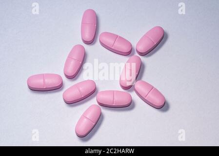 Pink pills on white paper. Group of pink medical pills on white background Stock Photo
