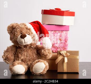 brown teddy bear and a stack of various cardboard boxes for gifts on a black table, white background Stock Photo