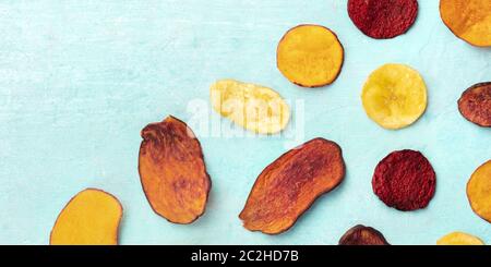 A panorama of dry fruit and vegetable chips, shot from the top on a vibrant teal blue background with copy space Stock Photo
