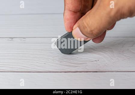 Eraser and error concept, Hand with black eraser on white table, Mistake erase concept Stock Photo