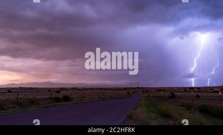 An electrical storm passes over farm land in Arizona Territory producing powerful lightning bolts Stock Photo