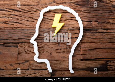 Lightning Idea Inside Head Silhouette On Wooden Desk Stock Photo