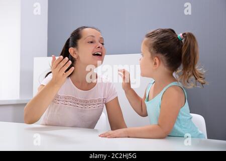 An Attractive Female Speech Therapist Helps The Girl How To Pronounce The Sounds In Office Stock Photo