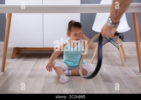 Father's Hand Holding Leather Belt In Hand Over His Daughter Hiding ...