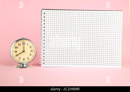 small vintage retro alarm clock and notebook on pink isolated background Stock Photo