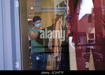 Woman shopping clothing store mall with protection face mask covid-19 quarantine. Young female choosing clothes during epidemic pandemic coronavirus.