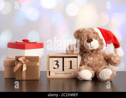 brown teddy bear and a stack of various cardboard boxes for gifts on a black table, white background Stock Photo