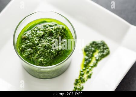 Fresh homemade basil pesto sauce in a glass jar. Originally from italy, pesto is commonly made with basil and used as a sauce for pasta. Stock Photo