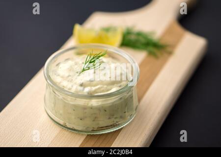 Homemade tartar sauce on black background. Made of fresh mayonnaise, lemon and various herbs. This classic creamy sauce is delicious with deep fried f Stock Photo