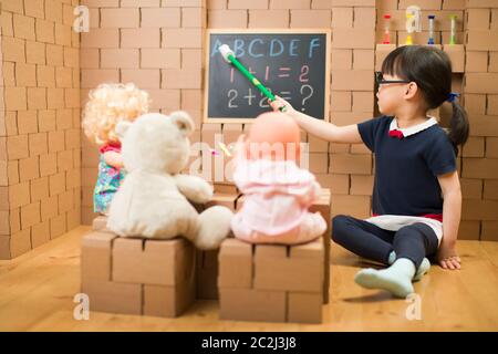 toddler girl pretend play as a teacher at home Stock Photo