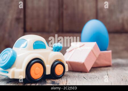 Easter egg and toy car on wooden background, happy easter day concept Stock Photo