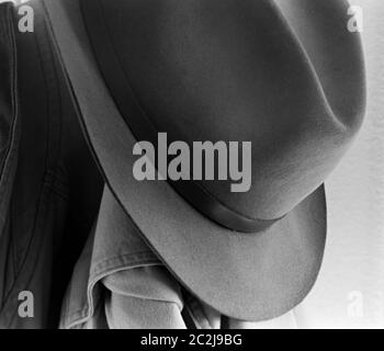1950s Fedora Hat Hung on a Coat Hook with a Canvas Field Jacket, Black and White Photograph, Close-up Stock Photo