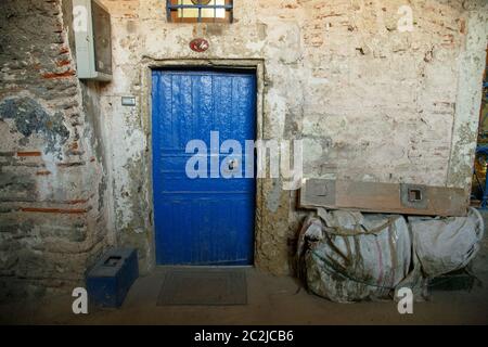 Old and worn blue wooden door with ironwork. Rustic blue door entrance to an old stone house Stock Photo