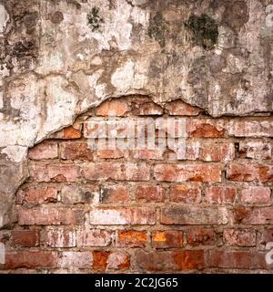Old brick wall in a background image. Plastered Brickwall With Chipped Stucco Pieces. Red Textured Brick Wall With Damage Surfac Stock Photo