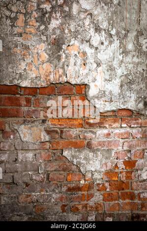 Old brick wall in a background image. Plastered Brickwall With Chipped Stucco Pieces. Red Textured Brick Wall With Damage Surfac Stock Photo