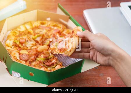 Hands taking pizza slices from green box Stock Photo