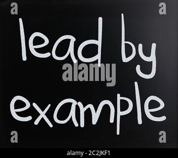 "Lead by example" handwritten with white chalk on a blackboard Stock Photo