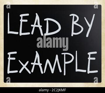 "Lead by example" handwritten with white chalk on a blackboard Stock Photo