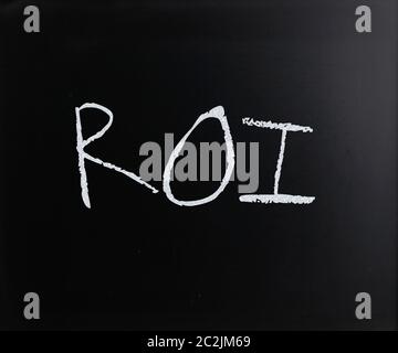 "ROI" handwritten with white chalk on a blackboard. Stock Photo
