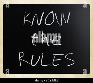 "Know the rules" handwritten with white chalk on a blackboard. Stock Photo
