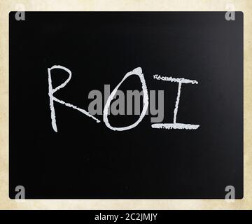 The word "ROI" handwritten with white chalk on a blackboard. Stock Photo
