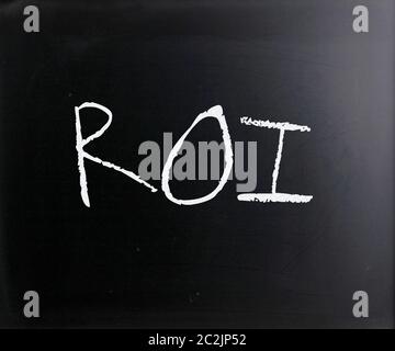 "ROI" handwritten with white chalk on a blackboard. Stock Photo