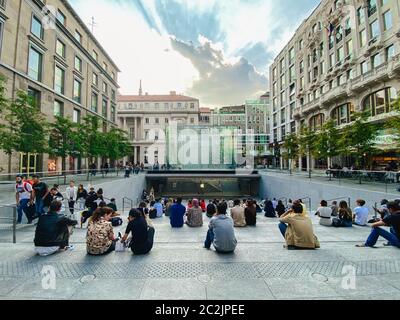 September 25, 2019 Italy. Milan. A lot of people are sitting on steps near apple store in Milan. On staircase, admiring the crys Stock Photo