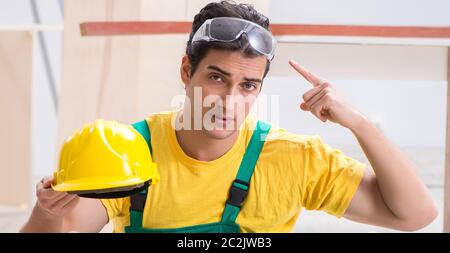 Carpenter wearing yellow hardhat in contractor workshop Stock Photo