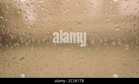 Rain Drops On Surface of wet Window Glass pane In Rainy Season. Abstract background. Natural Pattern of raindrops isolated from outdoor cloudy environ Stock Photo
