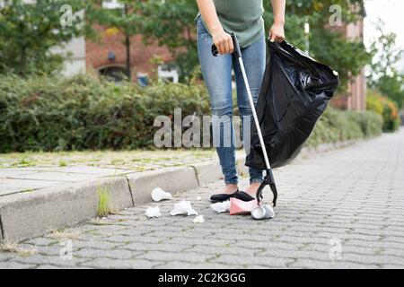 Woman Collecting Trash Outdoors Using Litter Picker Stock Photo